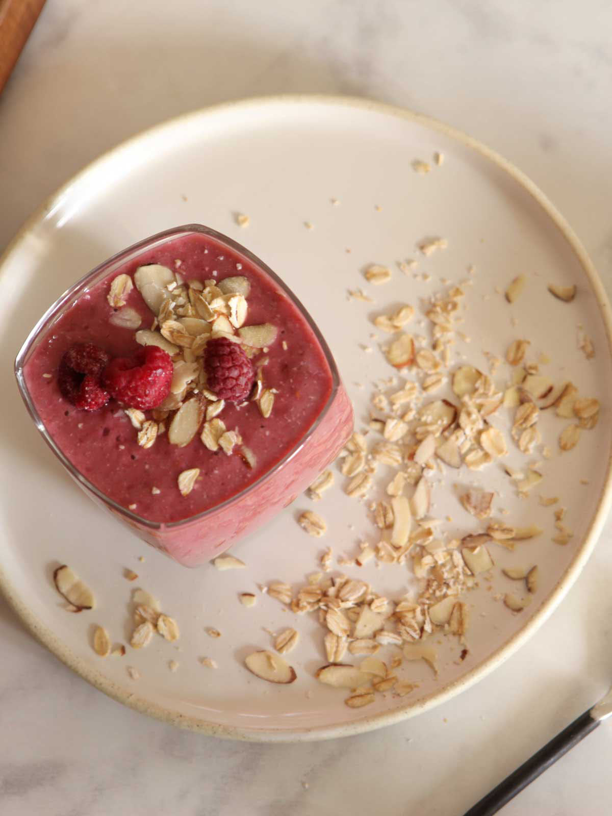 a glass of a dairy-free raspberry muffin smoothie with raspberries on top