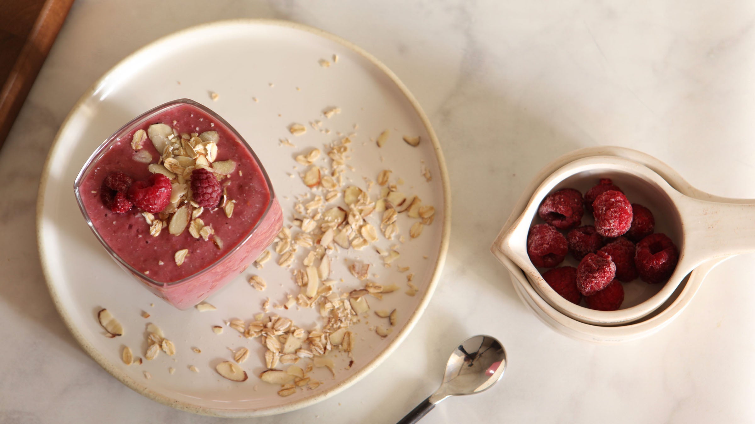 a glass of a dairy-free raspberry muffin smoothie with raspberries on top