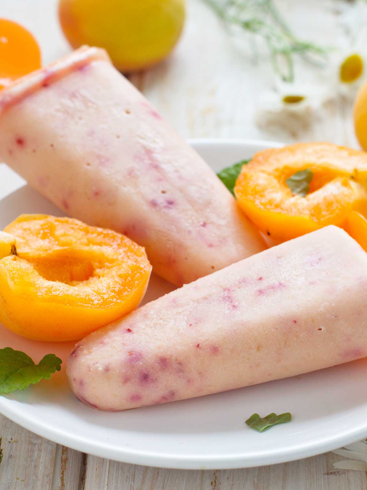 dairy-free peach basil popsicles with fresh sliced peaches on the side