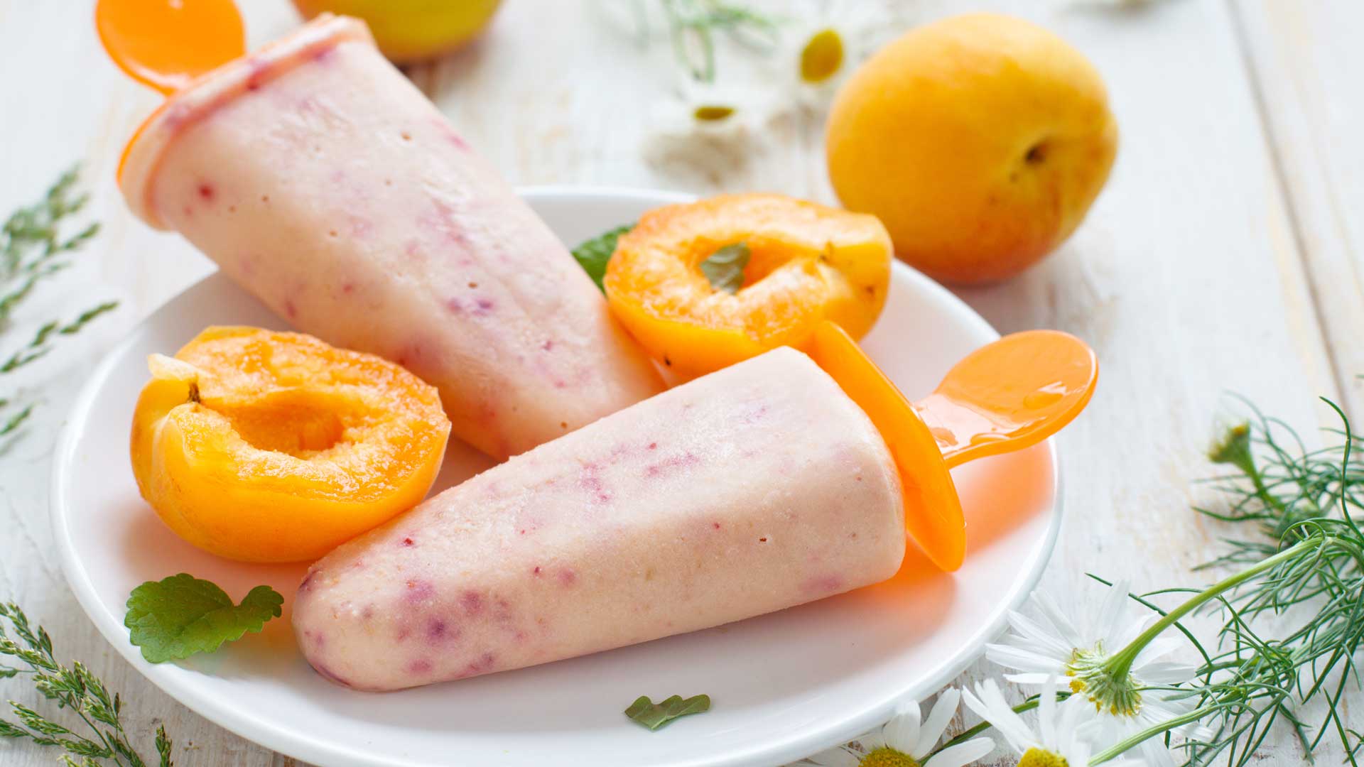dairy-free peach basil popsicles with fresh sliced peaches on the side